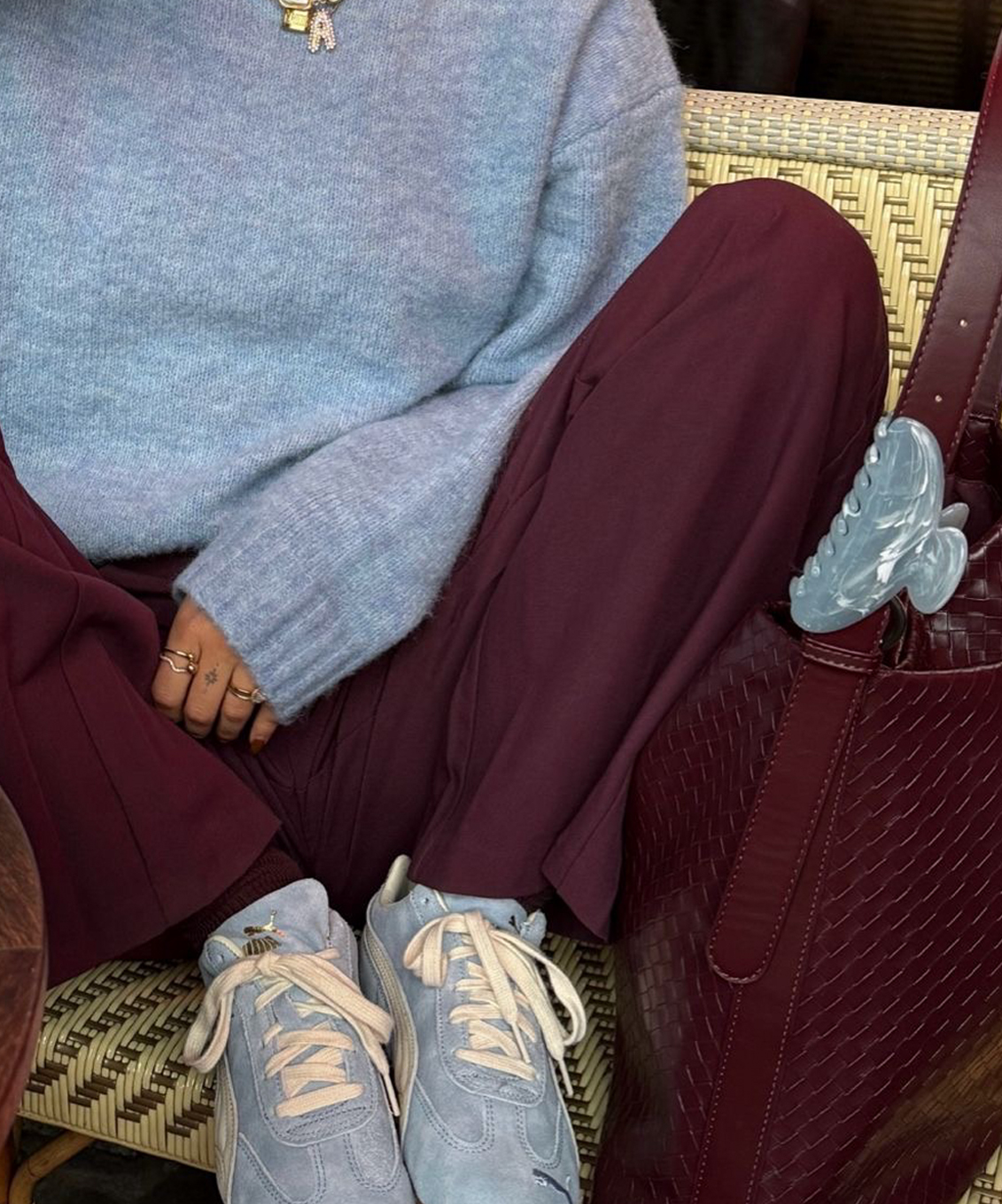 Personne portant un chandail bleu pâle et un pantalon bourgogne, avec des chaussures de sport bleues