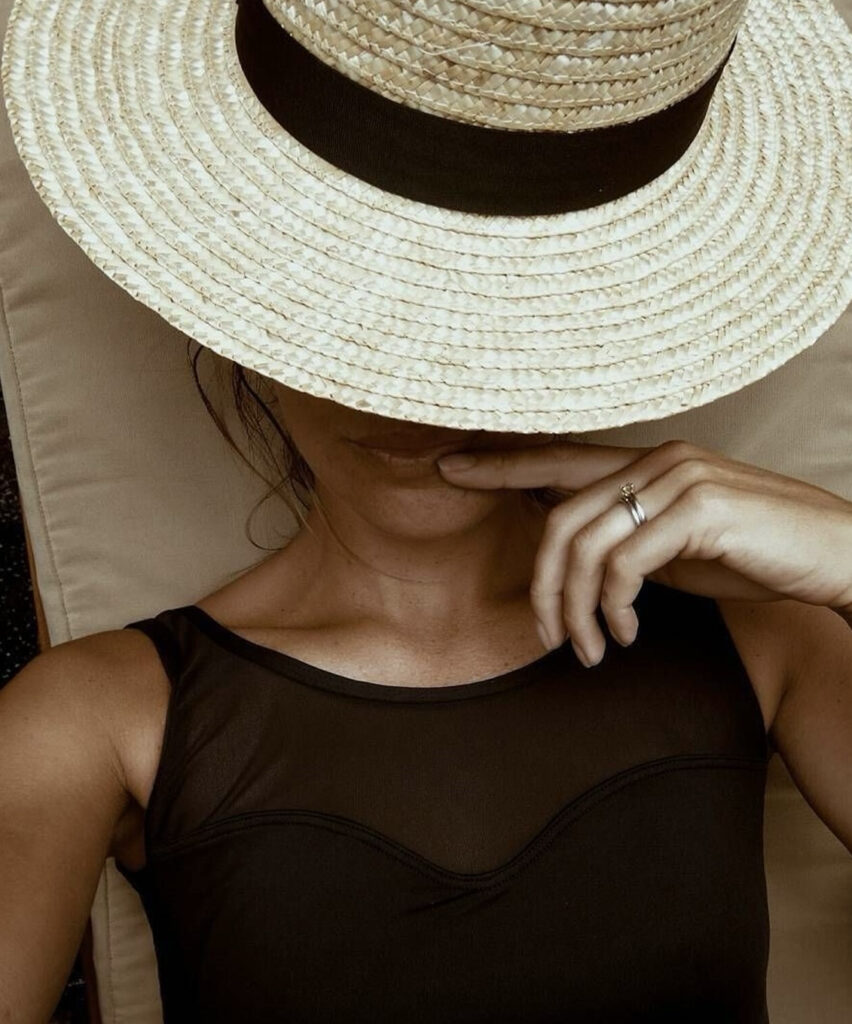 Femme portant un maillot de bain noir et un chapeau de paille.