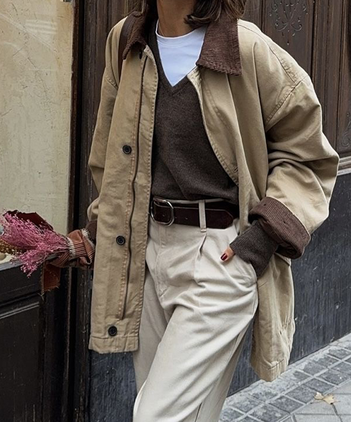 Femme portant un manteau beige, un chandail brun et un pantalon blanc