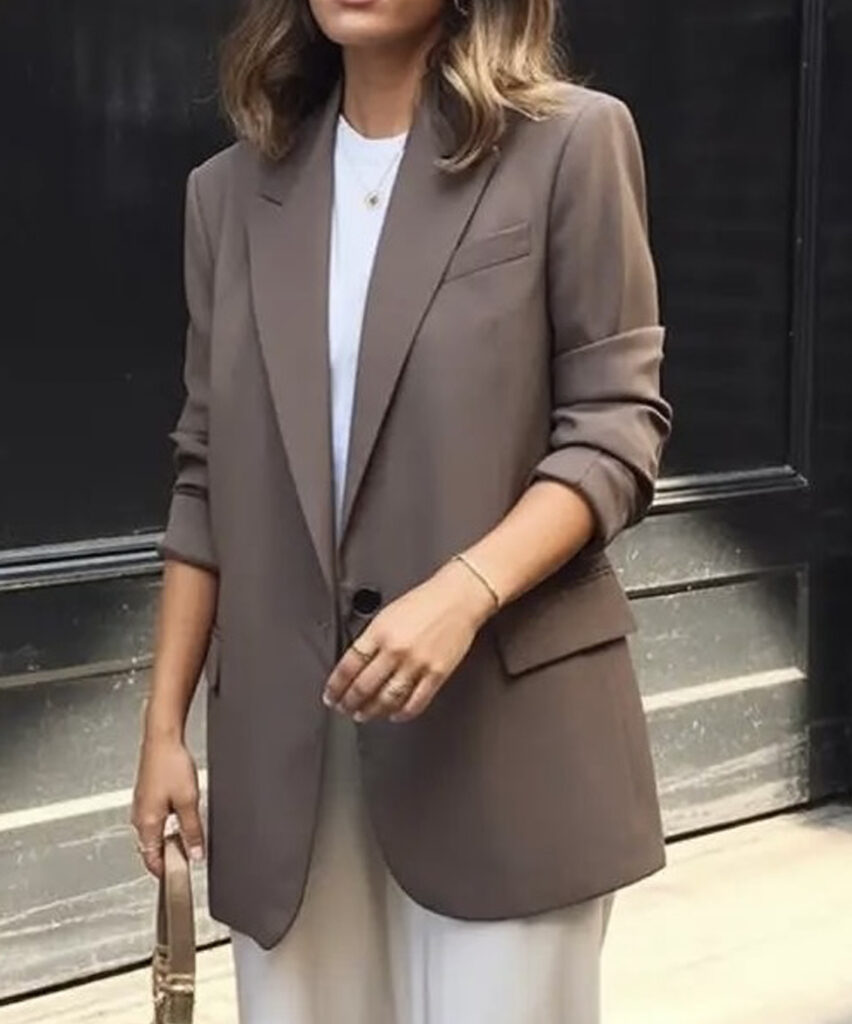 Femme portant un blazer brun avec un t-shirt blanc et un pantalon blanc.