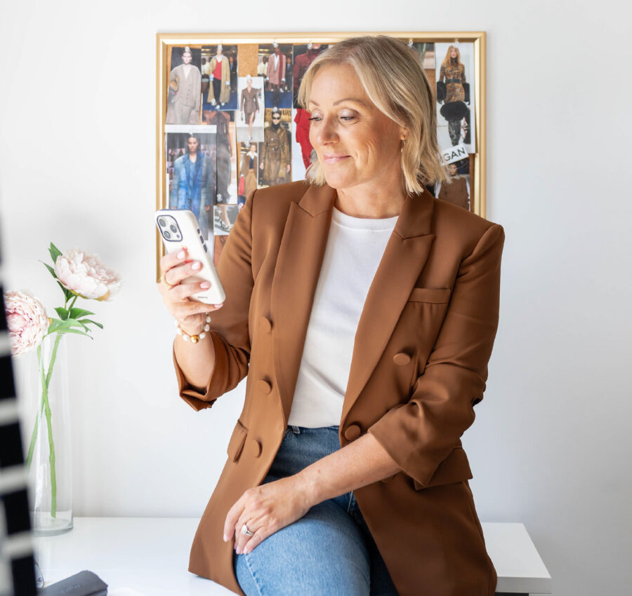 Catherine Côté consultant son téléphone, assise dans son studio de stylisme