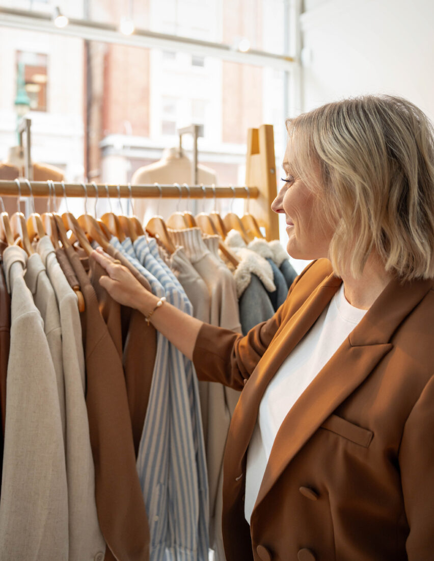 Catherine Côté parcourant un portant de vêtements en boutique