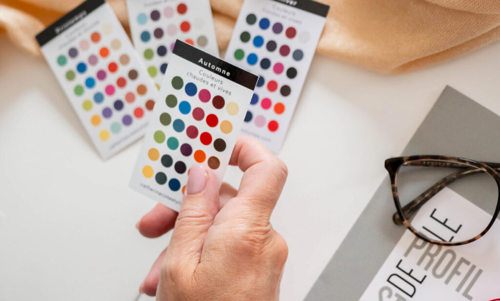 Main tenant un nuancier de colorimétrie près d’autres palettes de couleurs